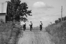 Amish men riding bikes on a dirt road 