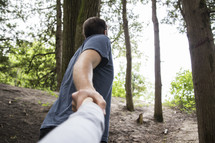 couple holding hands walking up a hill 