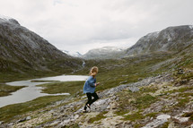 a woman running up a mountainside in Norway 