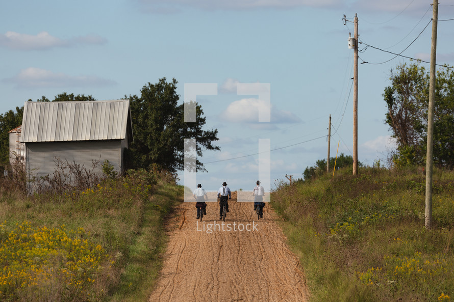 Amish boys riding bikes on a dirt road 