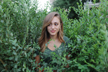 a young woman standing in a bush 
