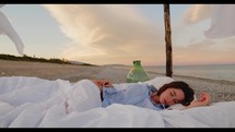 Girl sleep on the bed on the beach near the ocean