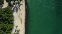Top-down (Bird's eye) view of sandy beach shoreline, water, and lighthouse 