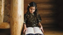 a little girl sitting on steps reading a Bible 