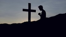silhouette a a man praying near a cross