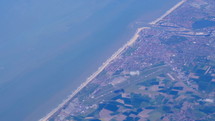 Aerial view of farmland area, cities and sea water landscape from airplane. View from window of airplane flying over Europe.