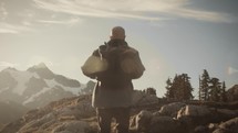 Man with backpack hiking in the mountains at sunset (or sunrise)