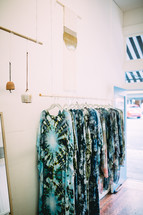 Tie dyed garments hanging against a white wall.