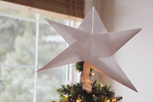 a handmade star out of simple folded paper by my son to decorate the top of the tree