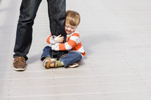 toddler boy hugging father's leg