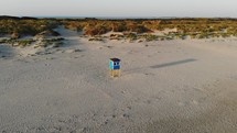 Aerial, orbit, drone shot, around a lifeguard post, at a beach, on a sunny evening, in Langeoog, Germany