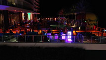 Aerial view of people hanging out at night on a rooftop poolside lounge with the DJ
