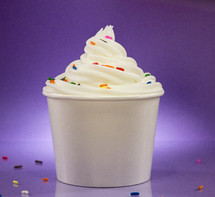 Cup of Vanilla Frozen Yogurt with Sprinkles Against a Purple Background