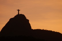 Jesus statue atop a hill at sunset