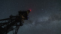 Milky way galaxy circling over communication tower in starry night sky Time lapse Zoom

