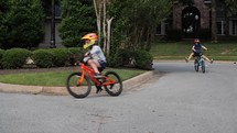 Three kids ride their bikes in the neighborhood