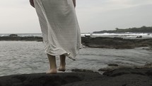 a woman walking on a rocky beach 