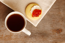 Tea or coffee time! Bird's eye view of tea or coffee with a sweet cookie or biscuit topped with cream and jam.