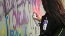 people spray painting graffiti on wall 