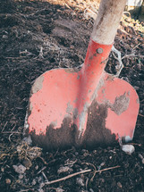 a red shovel digging into some dirt
