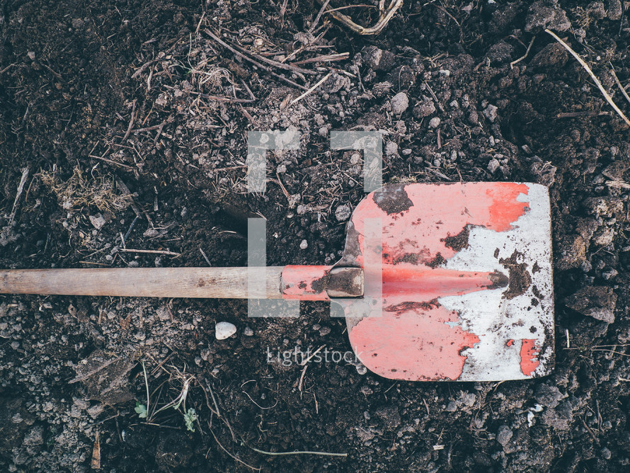 a red shovel sitting on dirt ready to be dug