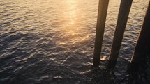 ocean water under a pier at sunset 