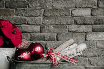 An arrangement of Christmas decorations against the backdrop of a gray brick wall.