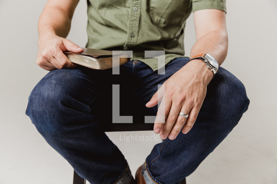 man sitting on a stool with a Bible in his lap