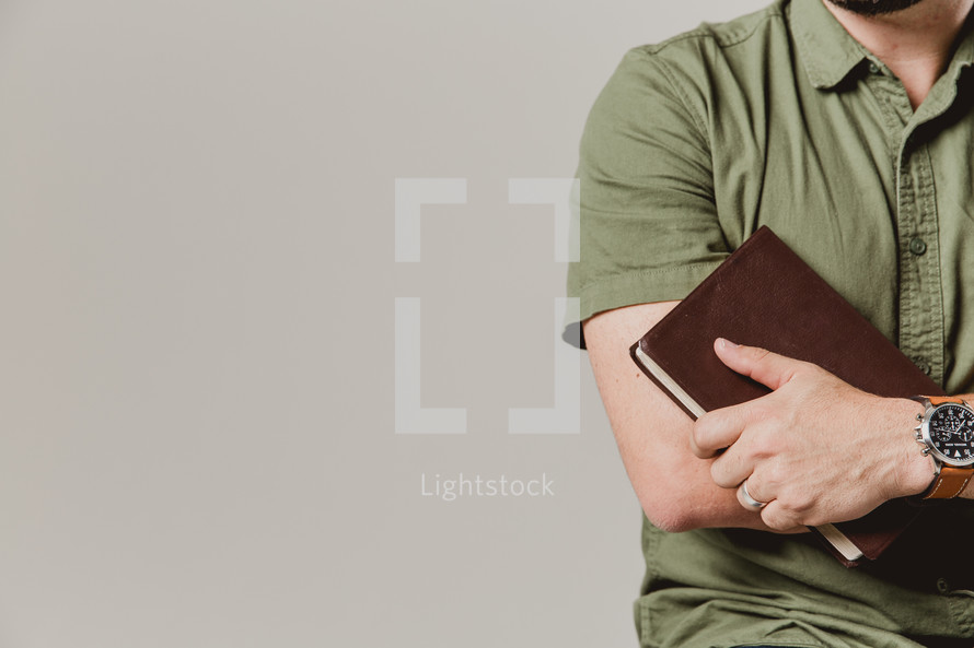 torso of a man holding a Bible 