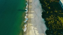 Drone footage up the beach surrounded by trees