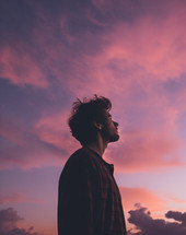A young man looking with head looking up towards the sky at sunset