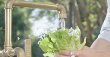 Slow motion shot of someone washing lettuce in an outdoor kitchen.