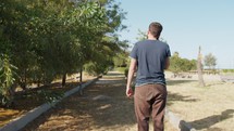 Man Talks On The Phone While Walking In A Park