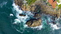 Top aerial drone view of waves crashing on rocky coastline