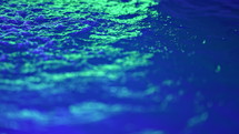 Blue water surface floating texture under neon green led light