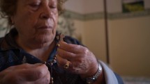 a senior woman praying with a rosary 