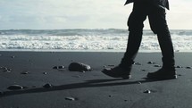 man in boots walking on a beach 