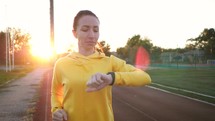 Concept healthy running. Young fitness woman running at the stadium. Runner woman with fitness tracker and running app wearable technology with smartwatch. Healthy lifestyle.