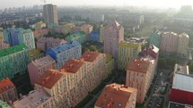 Row of multicoloured terraced houses. A new residential quarter with a colorful facade of high-rise buildings. Top view. Colorful buildings of a residential district. Urban landscape. Cityscape with multicolored houses, cars on the street. Top down view, drone video footage
