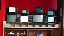 Stacks of vintage televisions on a wooden rack.