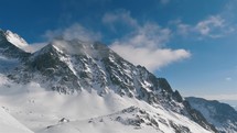 Panorama of winter alps mountains with rocky peak hidden in misty clouds in beautiful sunny snowy nature

