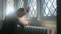 a man praying at a window 