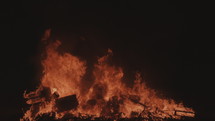 Camera tilt up on a massive bonfire at night