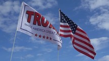 An American flag next to a Trump flag furling in the breeze