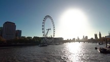 Low angle moving shot of London Eye ferris wheel over Thames River in London Great Britain