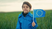 Little cute belgian boy with European union flag in green field. Happy child, kid smiling. Travel in Europe, EU future, education, traveling concept. High quality 4k footage