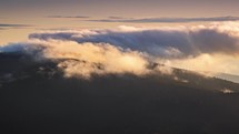Clouds moving fast over forest mountains in windy day at sunrise Time lapse

