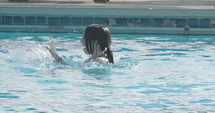 Super slow motion shot of boy and a girl playing and jumping in a swimming pool