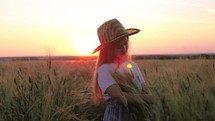 Pretty child in the wheat field. Happy young girl play in the field at sunset. Happy kid playing in the wheat field on a warm summer day at sunset.