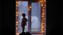 Child Looking out Window During Snow. 